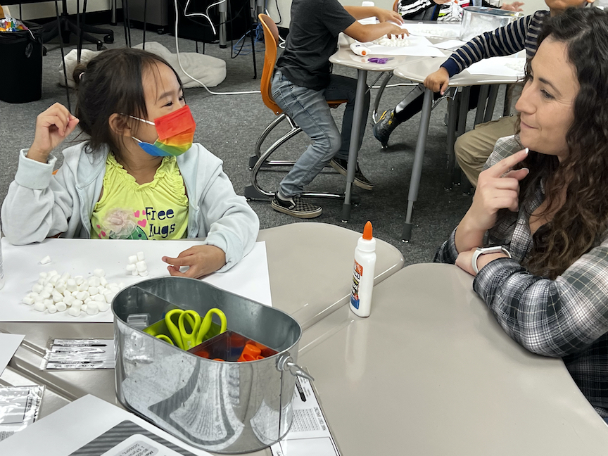 girl smiling at teacher at learning table