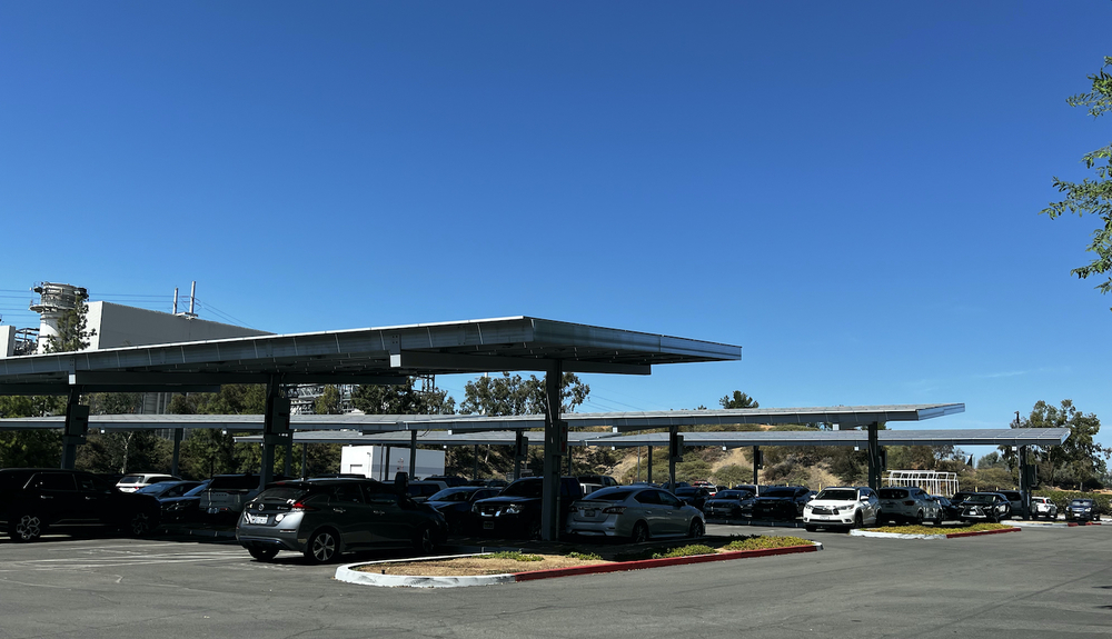 parking lot with cars and three rows of solar panels and blue sky