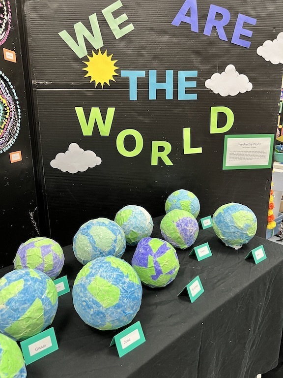 display of small papier mache globes with sign saying We are the world