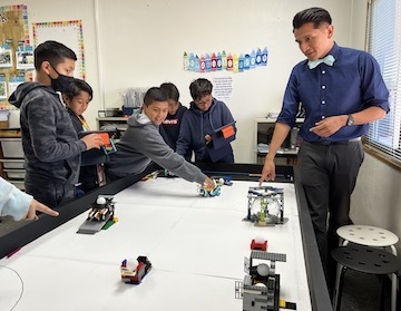teacher standing at lego robotics table with students