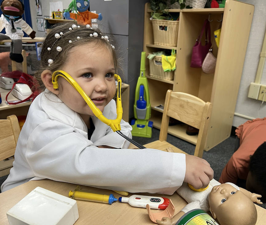 preschool girl with toy stethoscope and doll
