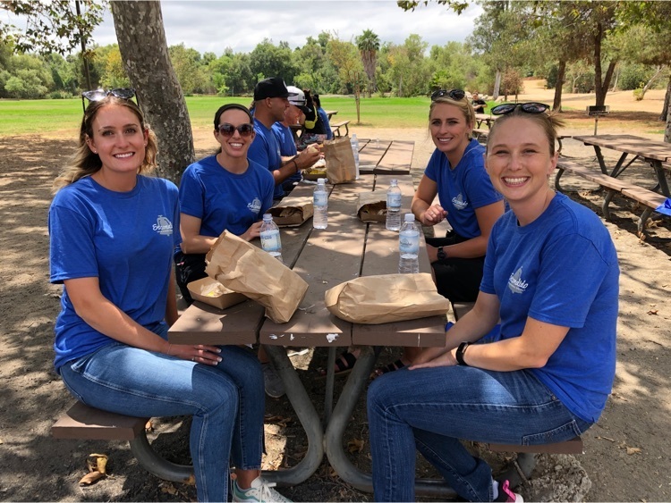 four women in blue shirts at picnic table outside 