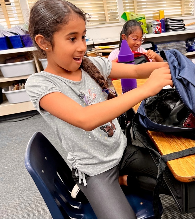 girl in gray t-shirt at desk opening backpack
