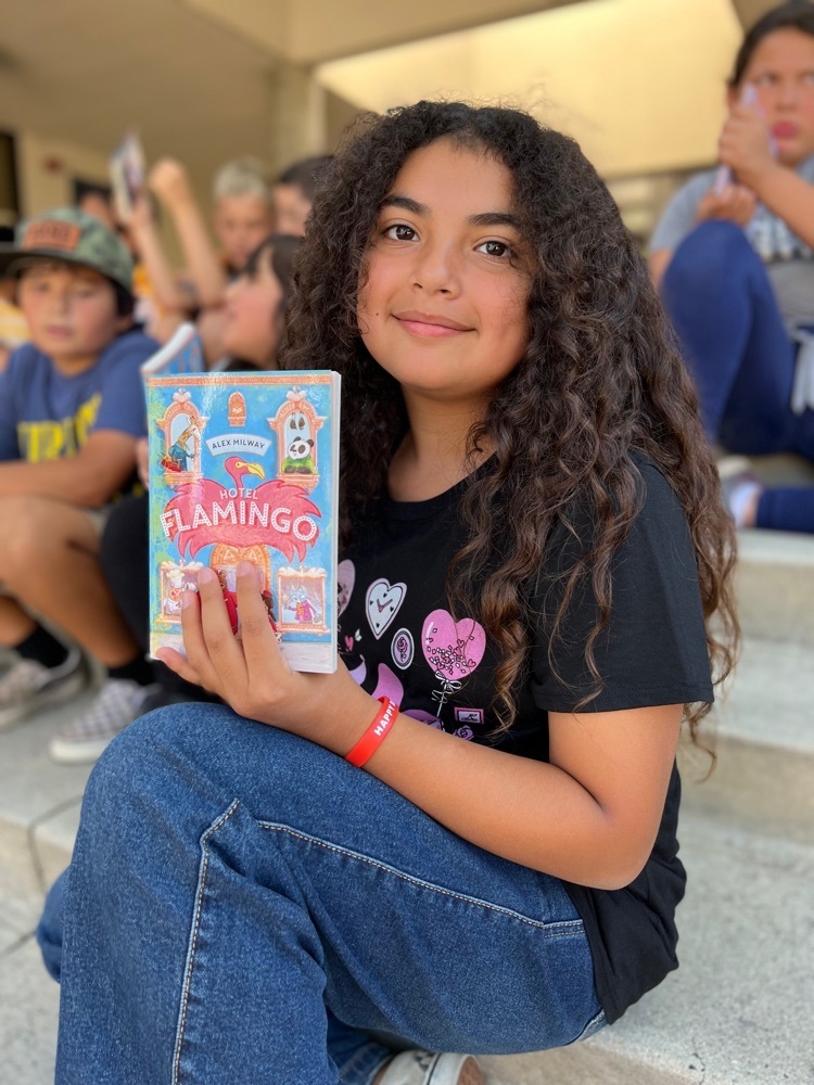 girl with long dark curly hair holding book