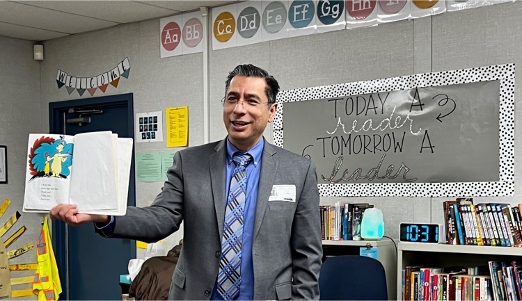 man smiling holding book in front of class