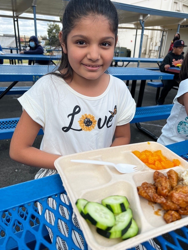 girl with lunch on tray with rice orange chicken and cucumbers