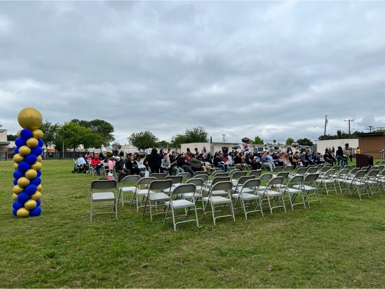 wide view of folding chairs on field with audience 