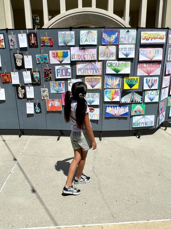 student looking at a black wall art display of other students artwork