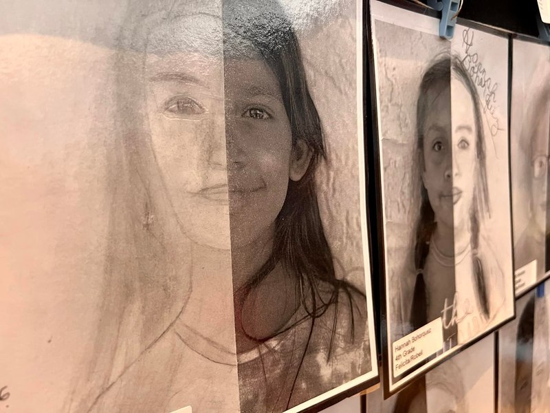 sepia drawings of faces by students at art show