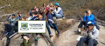 Cuyamaca Outdoor School logo over photo of students on boulders