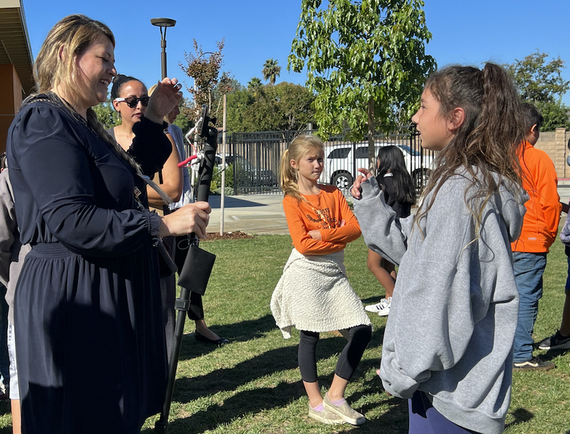 female reporter interviewing girl student outdoors