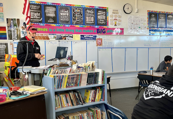 teacher wearing headset, rack of books