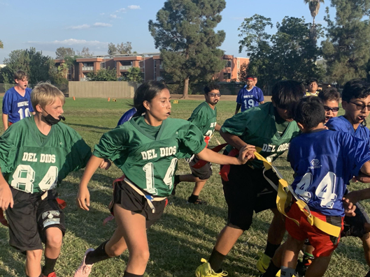 middle school students on field running playing flag football