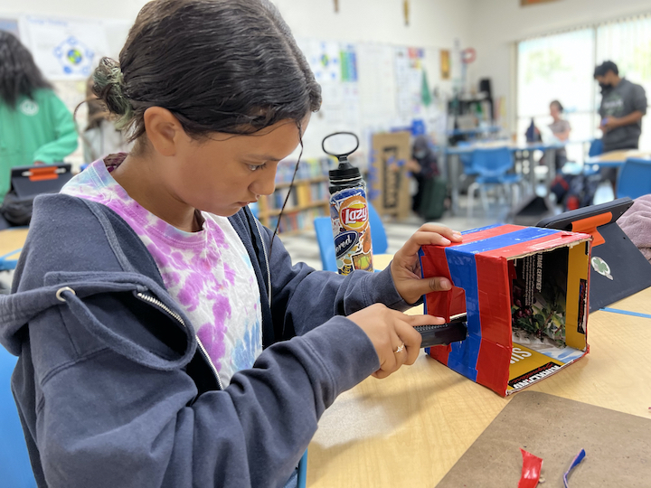 girl cutting cardboard for robot