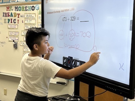 boy at smart board doing math problem